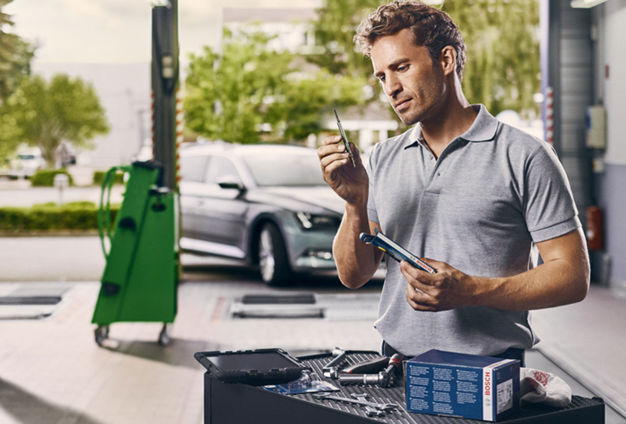 Man holding glow plugs in garage